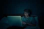 十几岁的男孩晚上在卧室看电脑图片素材