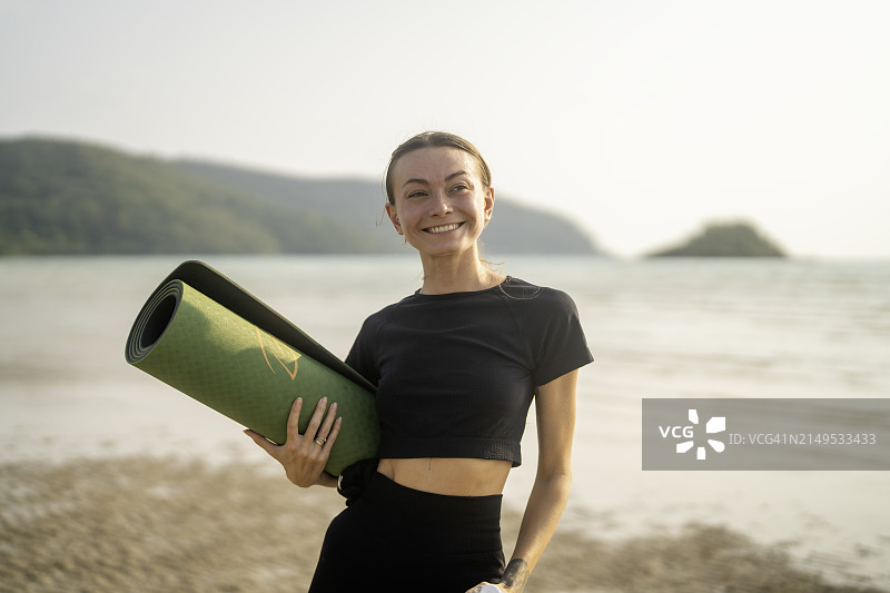 沙滩上拿着瑜伽垫的女人图片素材