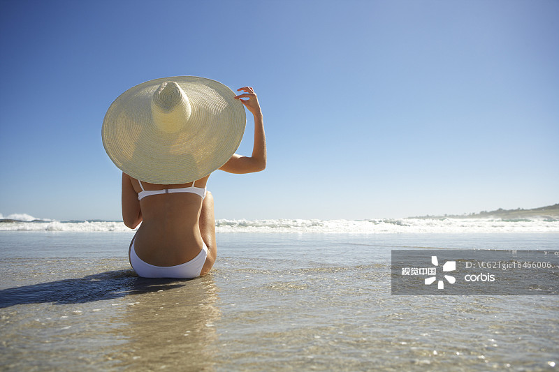 坐在海灘上戴太陽帽的女人圖片素材
