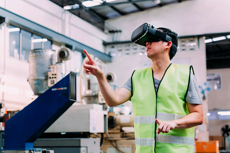在工廠里戴著虛擬現實模擬器的人做手勢圖片素材