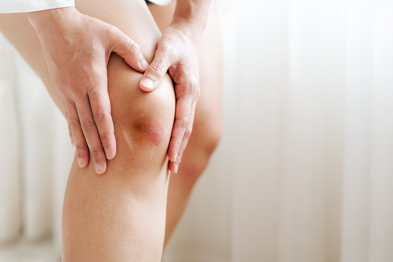 在疼痛中觸摸膝蓋的女人的腹部圖片素材