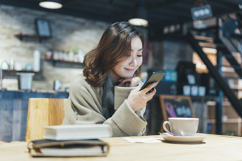 一個在咖啡廳喝咖啡發短信的女人圖片素材
