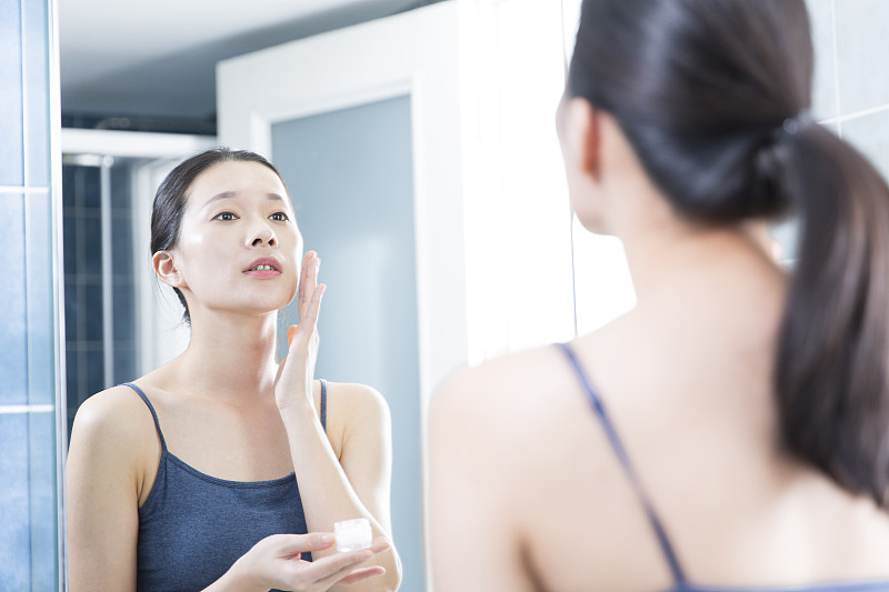 青年女子在衛生間照鏡子美容護膚圖片素材
