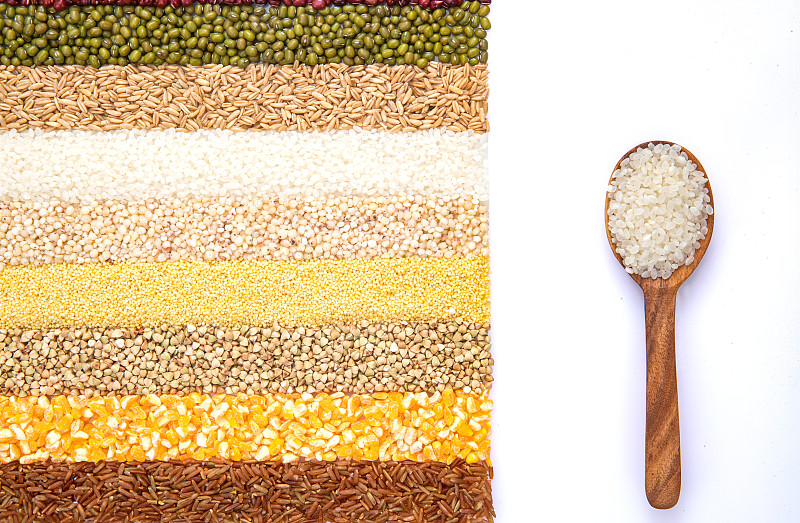 五谷雜糧平鋪和盛滿大米的木匙圖片素材