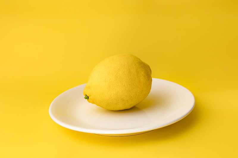 阿塞拜疆巴庫，黃色背景下的盤子里的檸檬特寫圖片素材