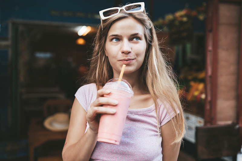 年輕的金發女人喝草莓奶昔，清邁，泰國圖片素材