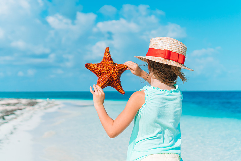 女孩抱著海星在海灘上圖片素材