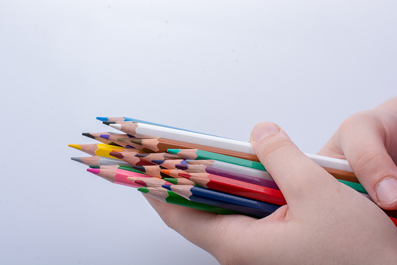 裁剪的手持彩色鉛筆在白色的背景圖片素材