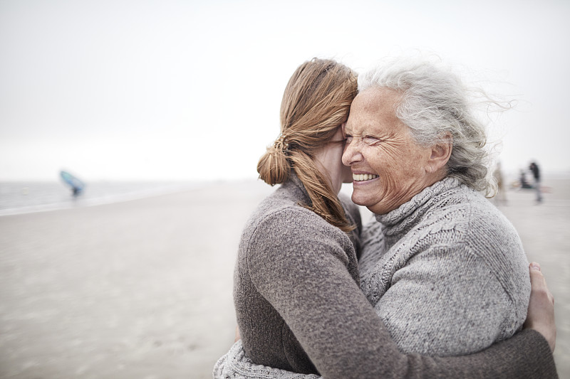 慈祥的祖母和孫女在海灘上擁抱圖片素材