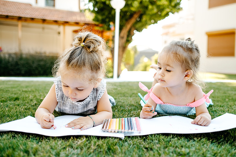 小女孩們在戶外草地上的畫紙上畫畫圖片素材