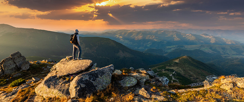 一個年輕人在山頂上看日落圖片素材