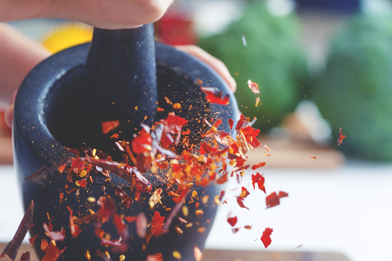 干辣椒被研缽和杵碾碎的動作畫面。圖片素材