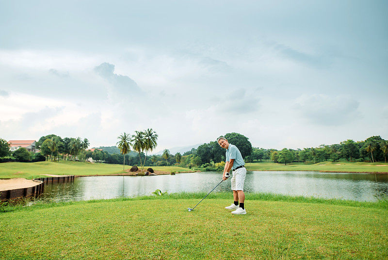 亞洲華人活躍的資深男高爾夫球手在高爾夫球場上打高爾夫球圖片素材