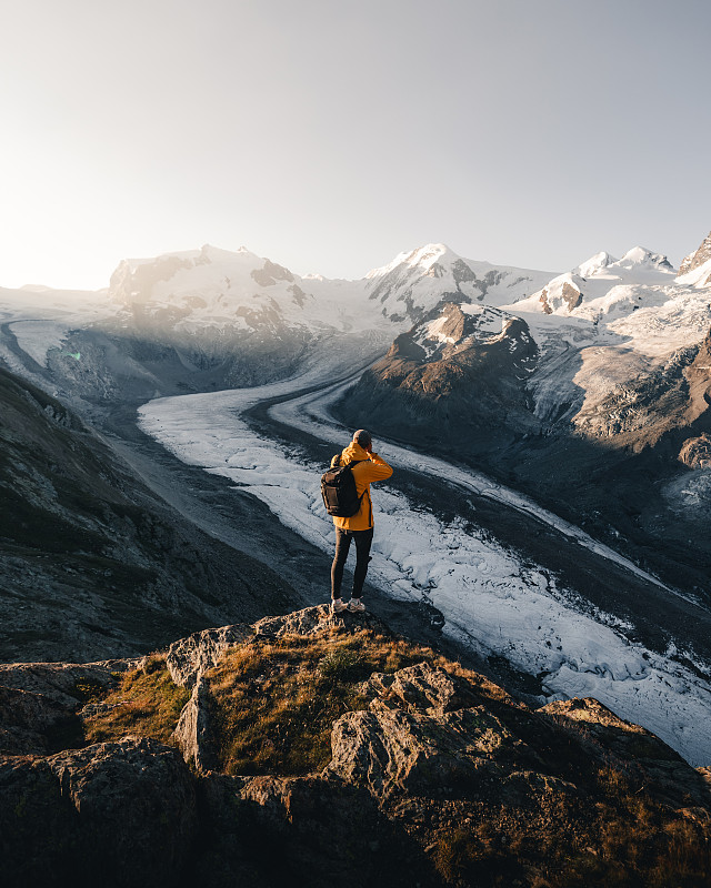 人站在白雪皚皚的山上的后視圖圖片素材