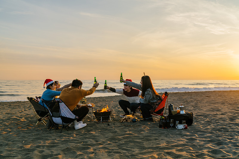 一群年輕的朋友在日落時分的海灘上慶祝圣誕節圖片素材