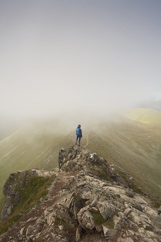 孤獨的女性在崎嶇的地形徒步，湖區，英國。攝影圖片