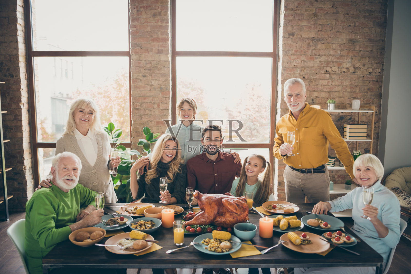 大家族围坐在餐桌上拥抱节日烤火鸡拍摄肖像八亲戚妻子丈夫几代人在客厅室内举起酒杯照片摄影图片