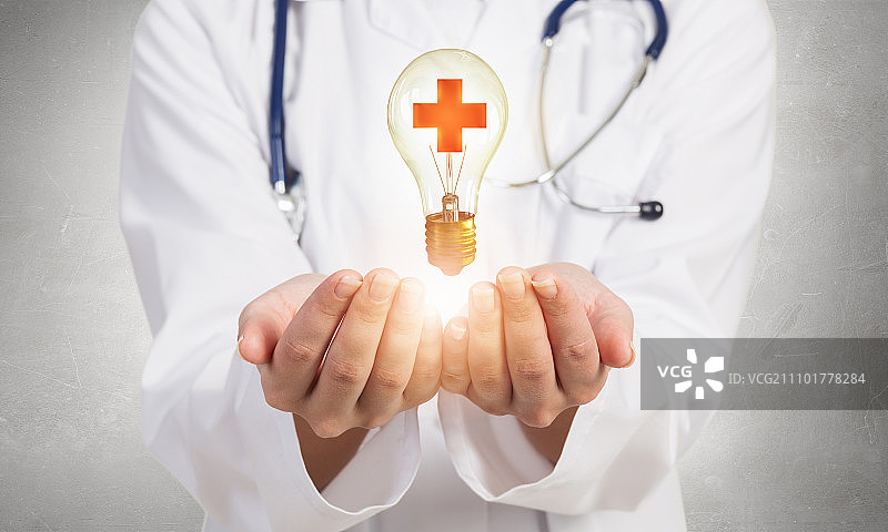 医学交叉的象征。白衣女医生，灯泡上有医学十字标志图片素材
