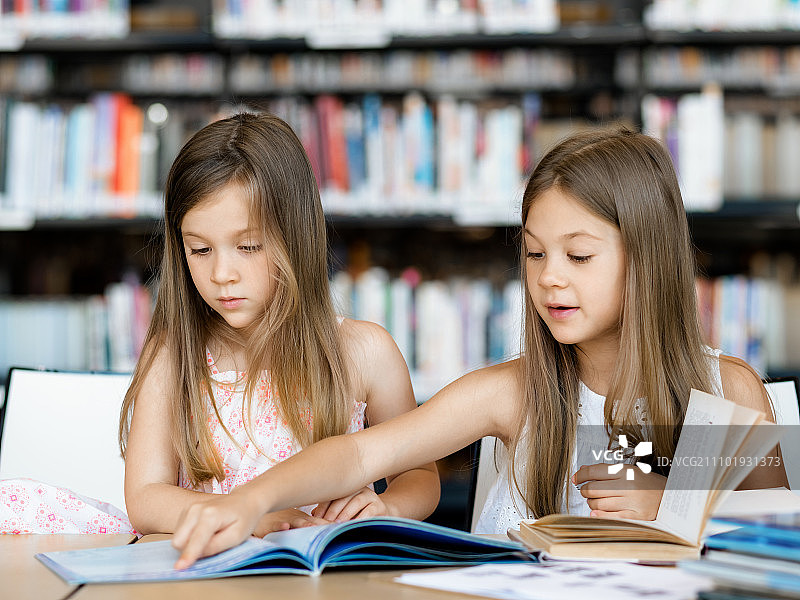 小女孩在图书馆看书。我们喜欢阅读图片素材
