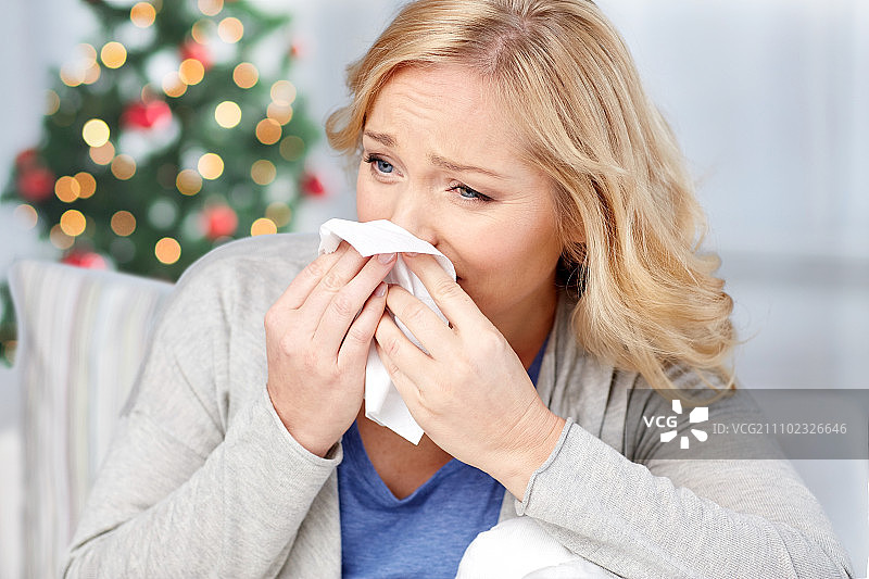 医疗保健，流感，圣诞节，和人们的概念-生病的女人擤鼻涕纸餐巾图片素材