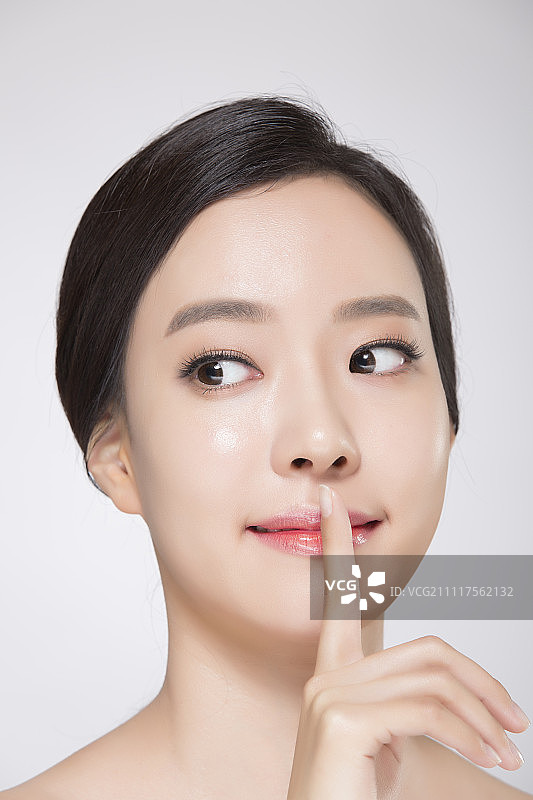 一个年轻女人的肖像与手指在她的嘴唇图片素材