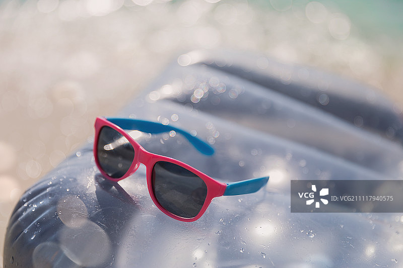 靠近粉红色和蓝色的太阳镜在充气筏在阳光明媚的水图片素材