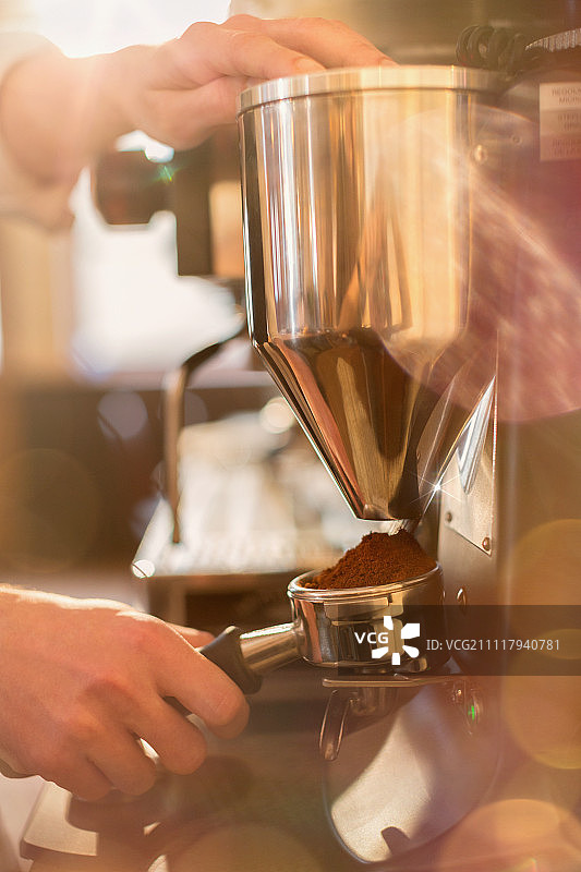 近距离使用浓缩咖啡机研磨机的咖啡师图片素材