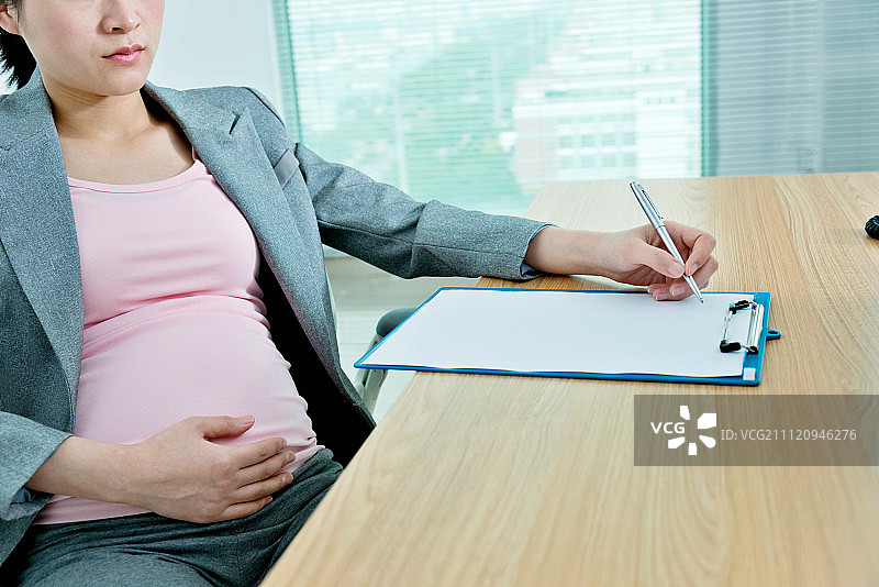 怀孕的商务女士在办公室书写图片素材