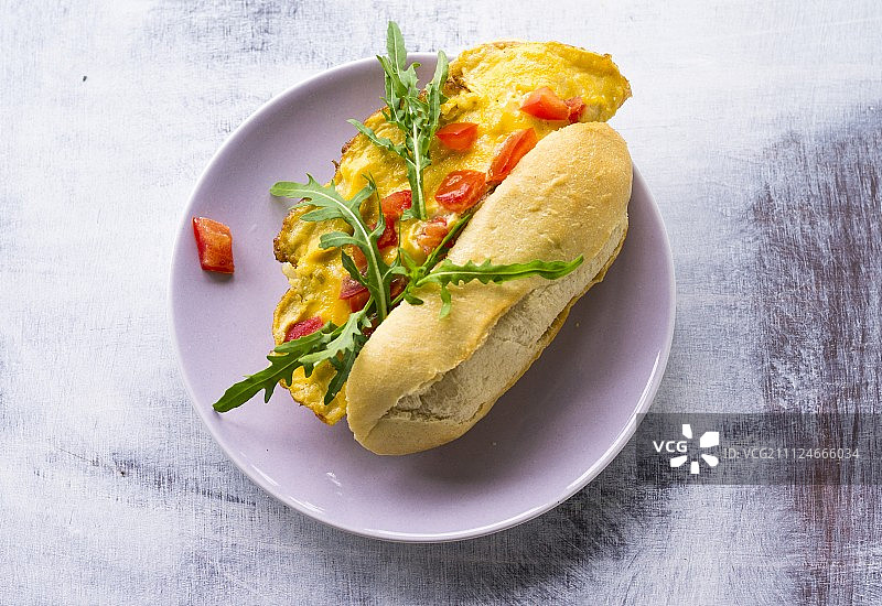 煎蛋汉堡配法式长棍面包，番茄和芝麻菜在盘子里图片素材