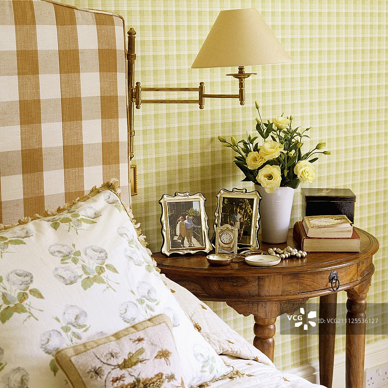 在床上放一些靠垫，旁边是古色古香的半圆形床头柜，用异国情调的木头做，靠墙是绿色格子墙纸图片素材