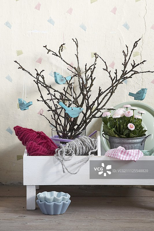 在白色花盆的锌盆里布置着浪漫的淡蓝色，在春天的枝头上挂着鸟形的装饰物和粉红色的肚脐图片素材