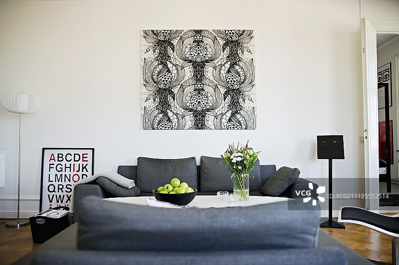 黑色和白色，图形艺术品在墙壁后面的灰色沙发组图片素材