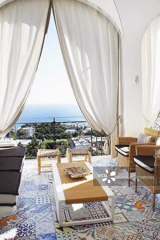 阳台上的座位用五颜六色的地中海地砖;透过拱门和卡普里湾的窗帘可以看到海洋图片素材