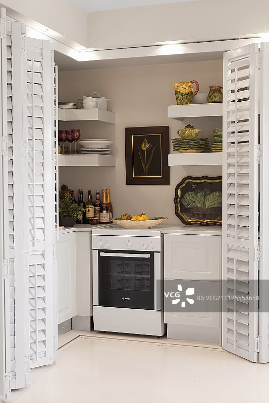 现代化的厨房配备了间接的天花板照明和白色的板条折叠门图片素材