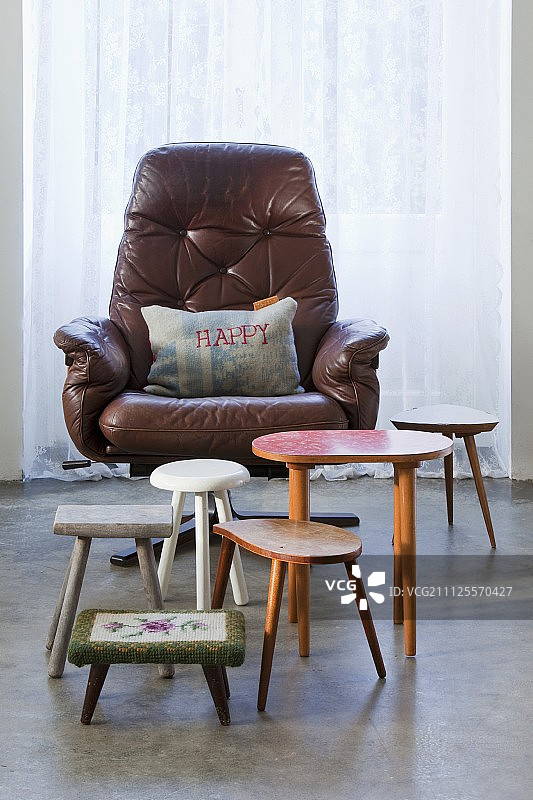 各种复古的凳子和边桌前面的坐垫与“快乐”主题的皮革转椅图片素材