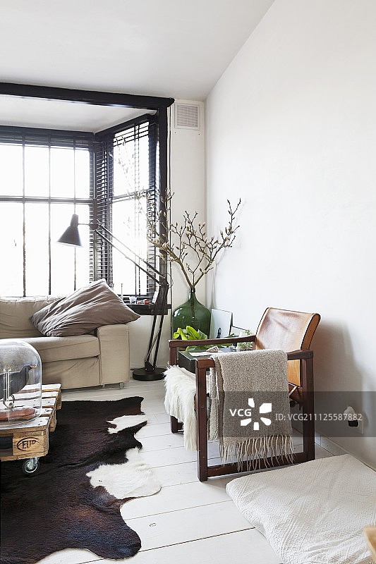 白色木地板上的木框真皮扶手椅，窗前的复古标准灯图片素材