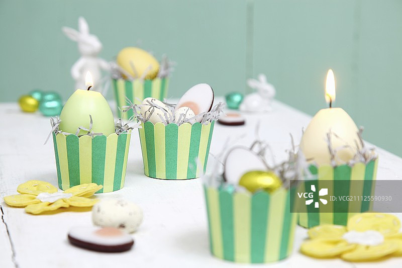 复活节安排黄色和绿色;条纹松饼盒里的蜡烛和糖果图片素材
