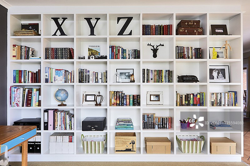 从地板到天花板的白色书架上放着书和储物篮图片素材