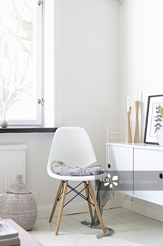 在角落的餐具柜旁边，白色的，经典的贝壳椅子，涂着白色的木地板图片素材