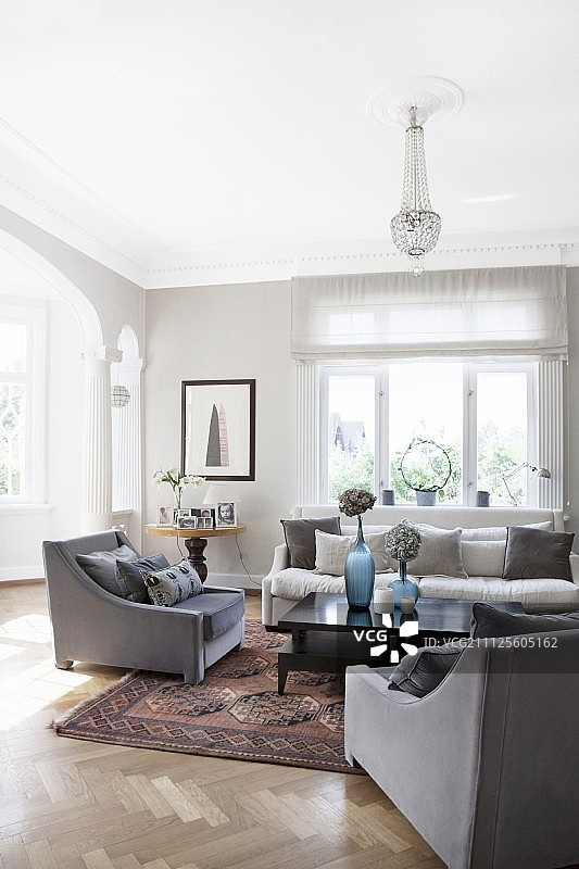 在质朴优雅的客厅里，黑色的咖啡桌周围是灰色的扶手椅图片素材