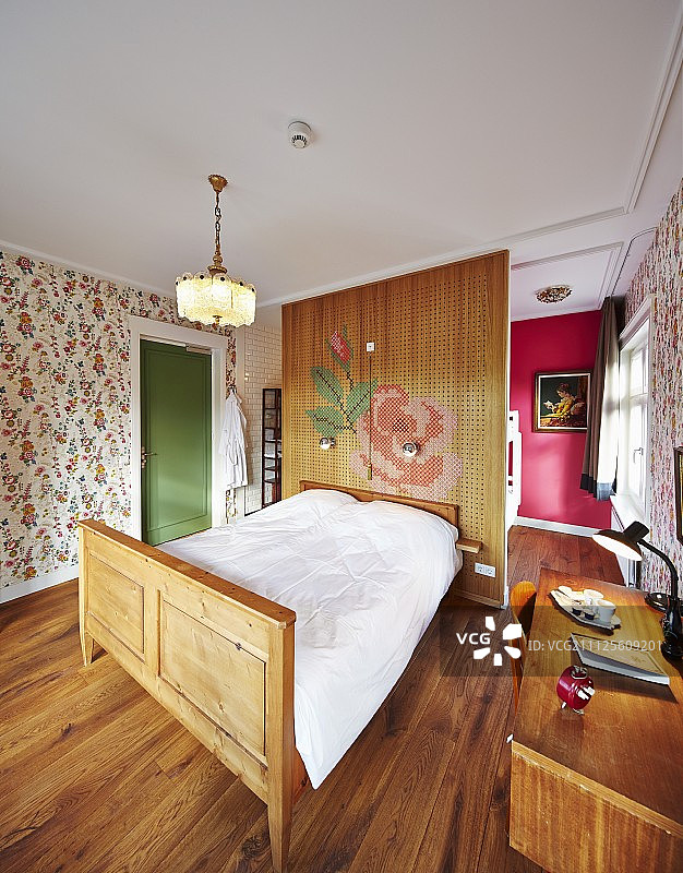 在复古风格的酒店房间里，有雕刻木框的双人床靠着隔墙和书桌图片素材
