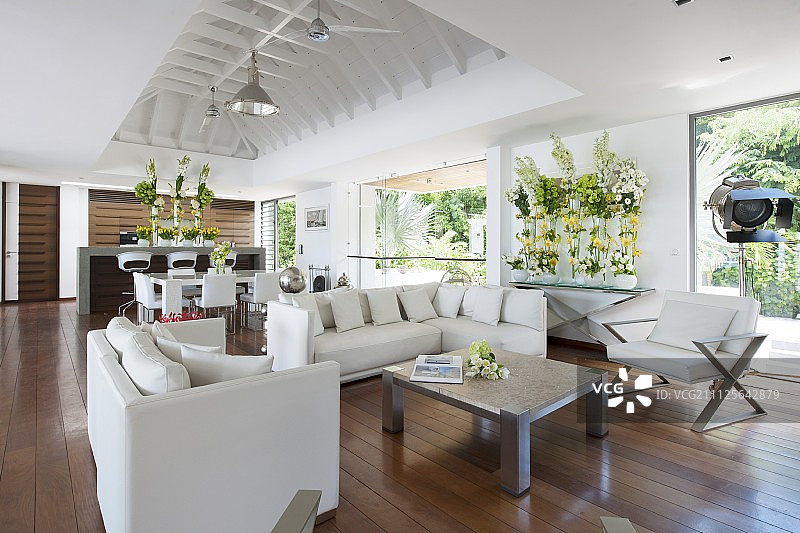 白色设计师家具和华丽的花卉安排在开放式的海滨别墅起居区图片素材