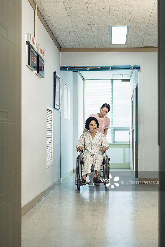 护士推着轮椅病人走过走廊图片素材