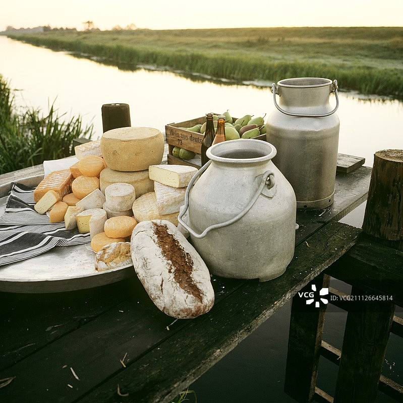 生奶奶酪和牛奶罐在河登岸码头上的静物图片素材