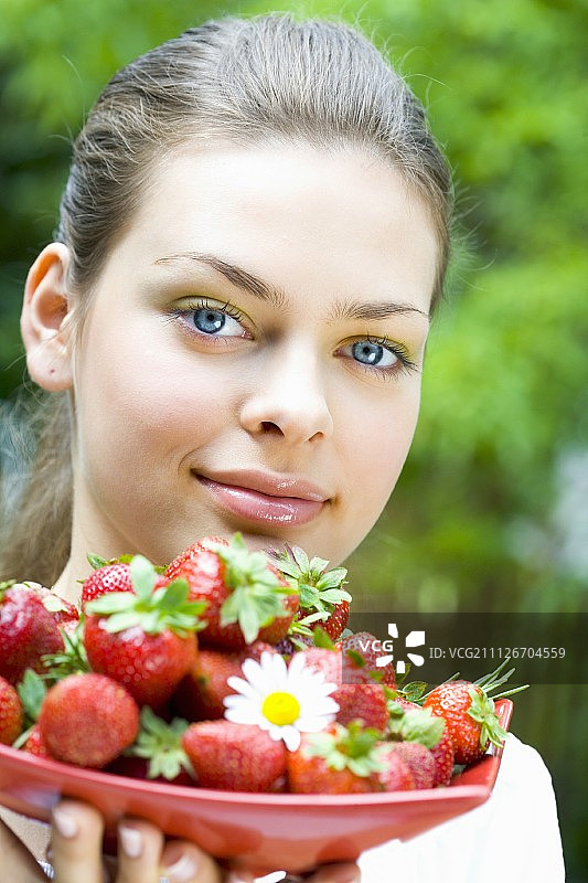一个年轻女子端着一盘草莓图片素材