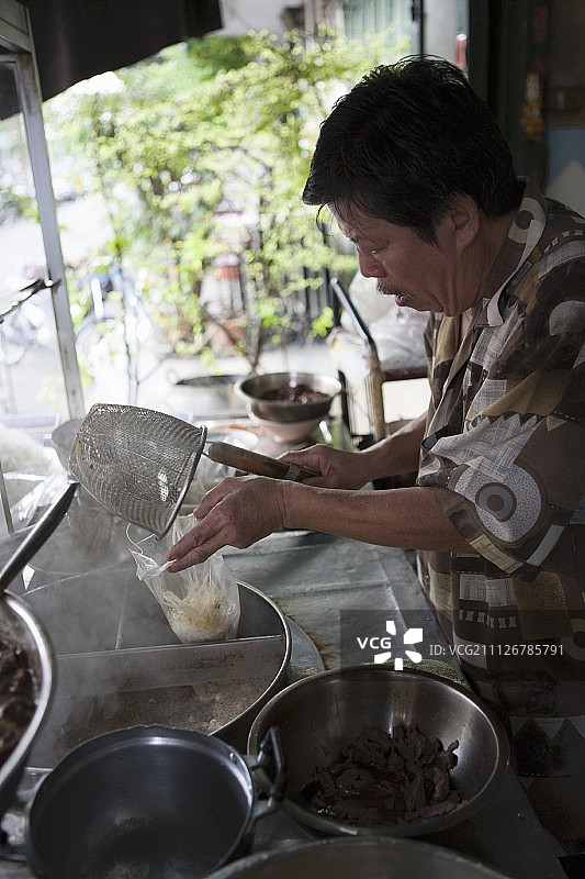 一名男子在泰国的一家烹饪店里做面汤图片素材