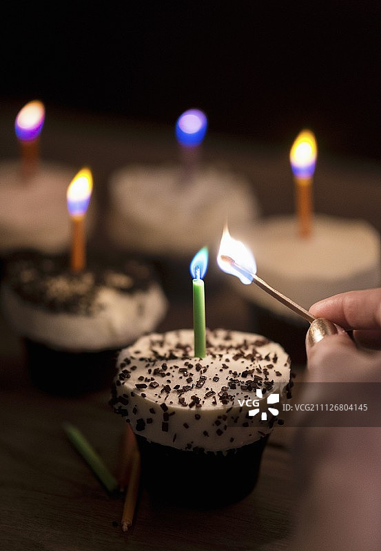 一个女人在节日纸杯蛋糕上点生日蜡烛图片素材