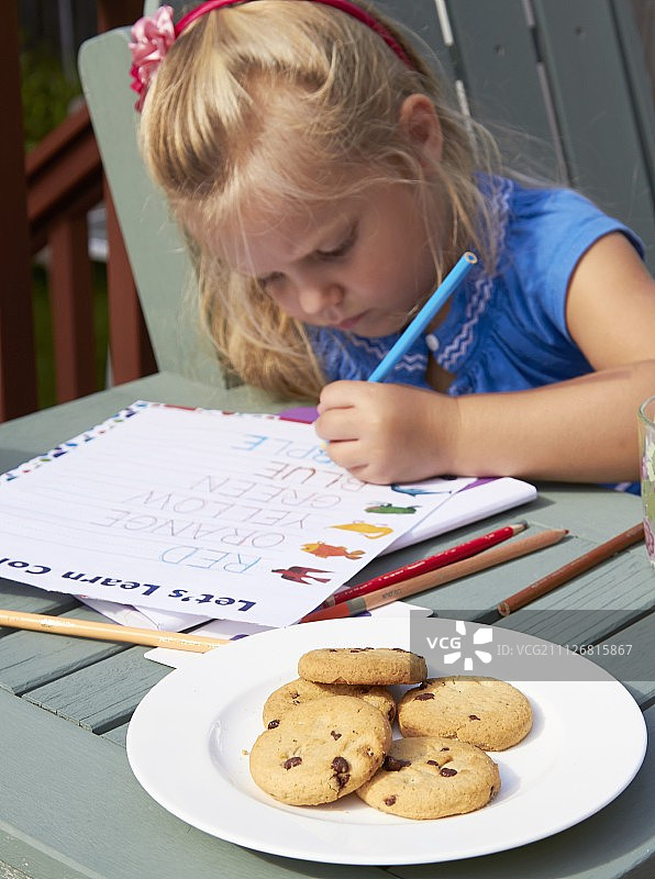 一个拿着课本和饼干的小女孩图片素材