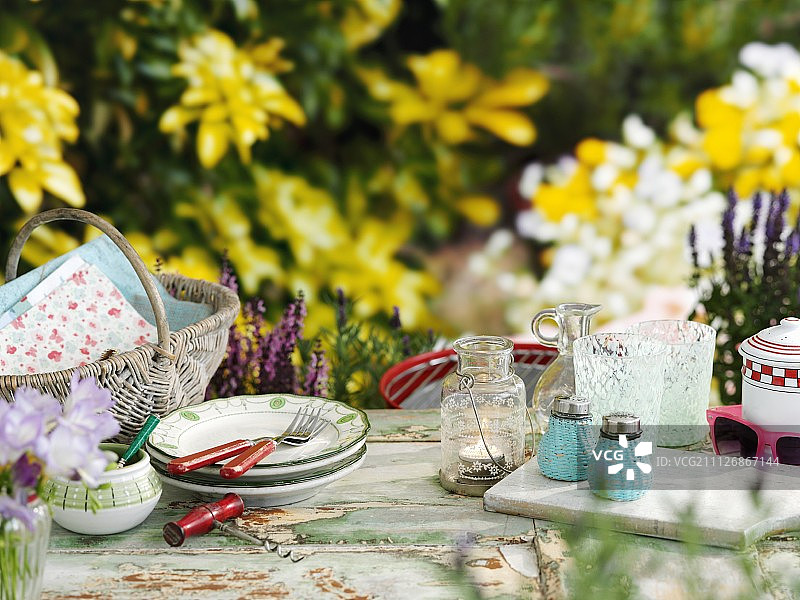 一个篮子、陶器、灯笼、玻璃杯、盐瓶和胡椒瓶放在夏日花园的桌子上图片素材