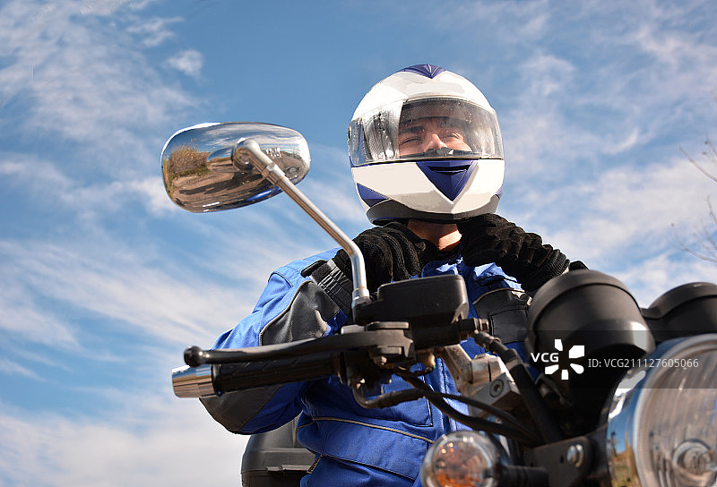 戴着蓝色头盔的摩托车手在路上行驶图片素材